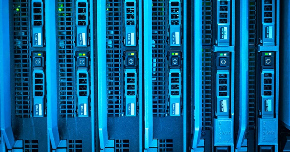 Rows of server racks lit blue along a data center aisle