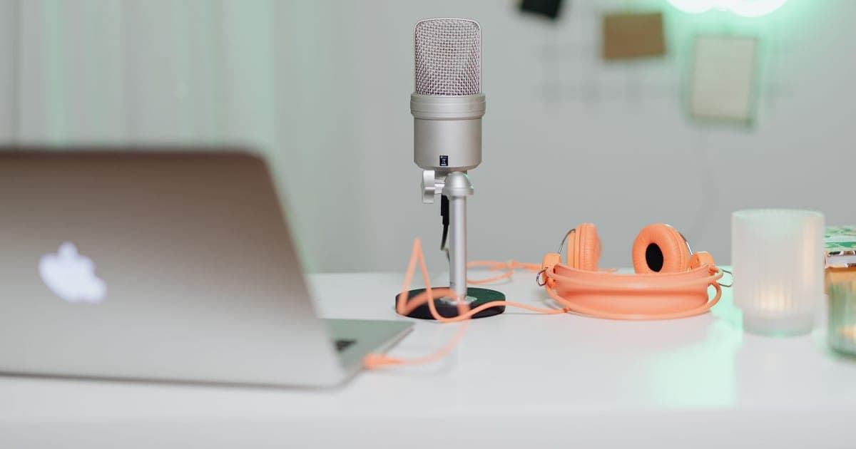 A silver microphone and a pair of headphones lying on a white table