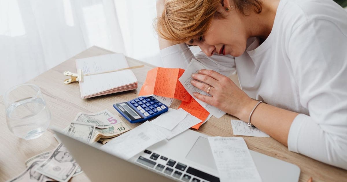 A woman at a desk sorting through a spread of paper receipts