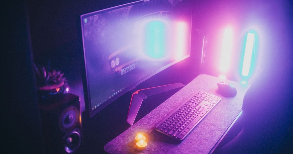 A monitor and keyboard lit by colored light in an otherwise dark room